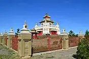 Overview of the monestary complex with white stupas on the fence, pagodas in the courtyard, and the monastery in the center