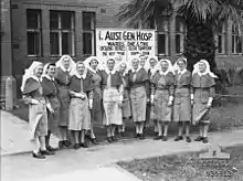 A group of nurses stand in front of a brick building