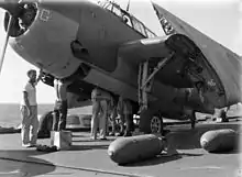Black and white photograph of an aircraft being loaded with bombs