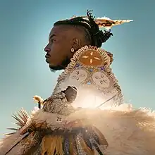 Two photos of Chief Xian aTunde Adjuah overlaid on one another with him wearing Native American garb