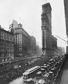 The Times Tower as seen in 1919, with its original marble facade. There are pedestrians and vehicles on the streets surrounding the tower.