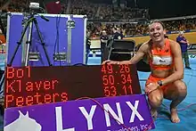Photo of Femke Bol crouching next to an electronic score board that indicates a time of 49.26 seconds