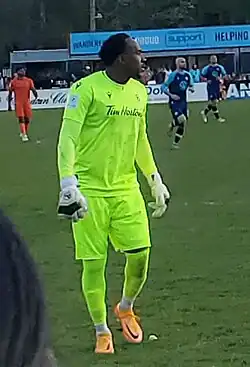 Goalkeeper dressed in a green kit looking to his right during a match