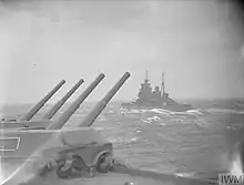 Black and white photograph of a warship in rough seas