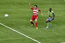 Zakuani vies against a Dallas player for the ball