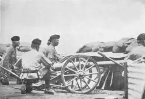 Three artillerymen crouch behind a small 2.5 inch "Screw Gun" employed in the defence of Kimberley