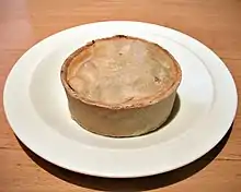 A circular pie, about 8 cm in diameter and 4 cm high, on a dinner plate, with no accompaniments