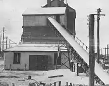 Covered conveyor leading upward and into the side of an industrial sheet metal building