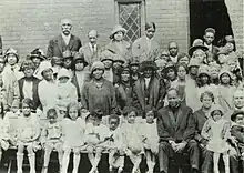 Group photograph of Black church members standing in several rows in front of the church.